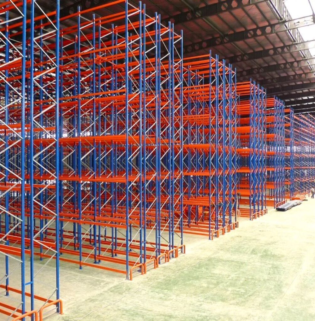 Double deep pallet racking system in warehouse with tall blue uprights and orange beams